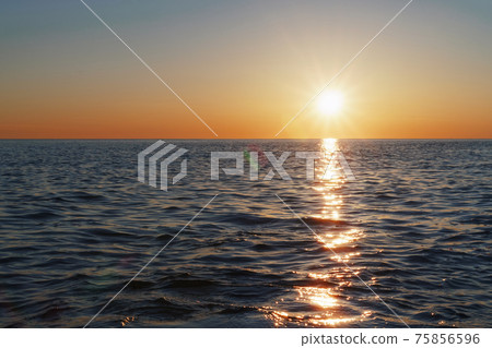 A sunny sunset on the sea stretching into the horizon with a path and highlights on the sea. 75856596