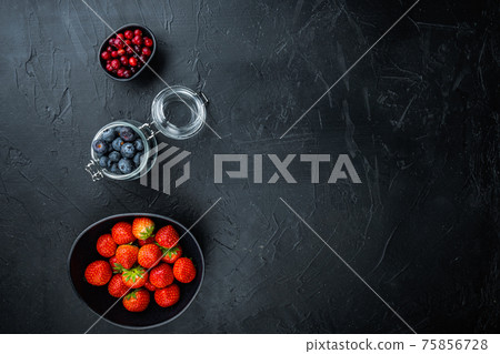 Ripe strawberry, cranberry and blueberry in bowl, top view with space for text, on black background Ripe strawberry, cranberry and blueberry in bowl, top view with space for text, on black background 75856728