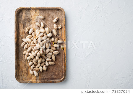 Shelled unsalted pistachios, on white textured background, top view with space for text Shelled unsalted pistachios, on white textured background, top view with space for text 75857034