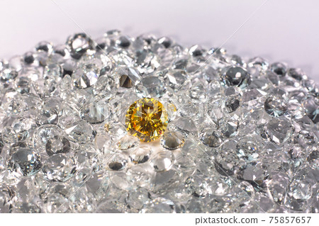 Yellow sapphire diamond on a pile of white diamonds. Yellow sapphire diamond on a pile of white diamonds. 75857657