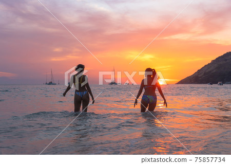 .Two women playing on the beach in the beautiful sky. .Two women playing on the beach in the beautiful sky. 75857734