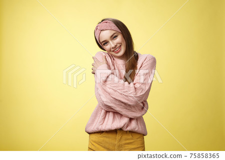 Girl feeling warm and safe thanks charming boyfriend embracing herself romantically hugging leaning on shoulder enjoying warmth of fluffy sweater, smiling tender in love over yellow background 75858365
