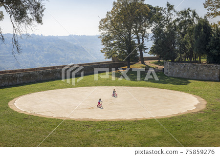 Park with round playground and children on bicycles in Orvieto, Umbria, Italy Park with round playground and children on bicycles in Orvieto, Umbria, Italy 75859276