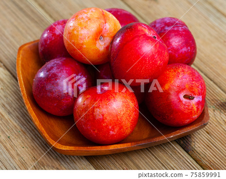 Close-up of fresh juicy red plums on wooden surface Close-up of fresh juicy red plums on wooden surface 75859991