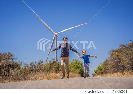 Alternative energy, wind farm and happy time with your family. Happy father on the road with his son on vacation and escape to nature. Father and son waving their arms like a windmill Alternative energy, wind farm and happy time with your family. Happy father on the road with his son on vacation and escape to nature. Father and son waving their arms like a windmill 75860013