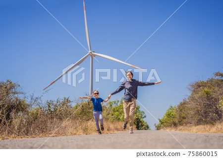 Alternative energy, wind farm and happy time with your family. Happy father on the road with his son on vacation and escape to nature. Father and son waving their arms like a windmill Alternative energy, wind farm and happy time with your family. Happy father on the road with his son on vacation and escape to nature. Father and son waving their arms like a windmill 75860015