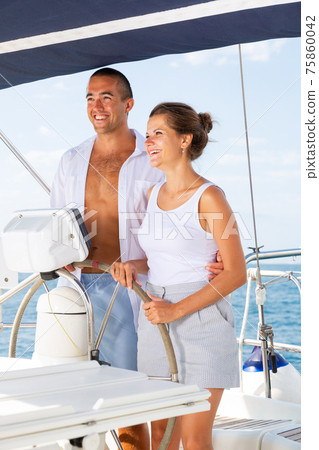 Man and woman steering pleasure yacht 75860042