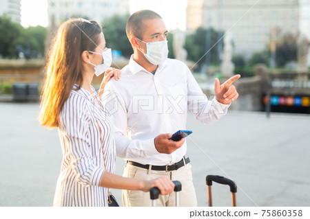 Tourist couple in medical masks visiting city attractions Tourist couple in medical masks visiting city attractions 75860358