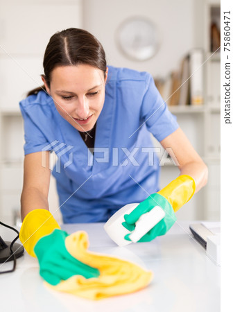 Cleaning lady of cleaning company wipes dust from table in office 75860471