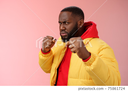 Serious-looking angry irritated young black bearded man pissed rude person attidude raise fists frowning grimacing anger furious feel punch face standing boxing pose wanna fight pink background 75861724