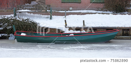 Green small boat stuck in frozen ice Green small boat stuck in frozen ice 75862890