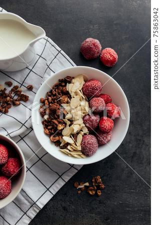 Frozen strawberry with granola, almond flakes, cream on concrete table 75863042