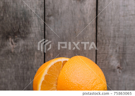 Halves of orange fruit on gray wooden background. Orange pulp and green leaves 75863065
