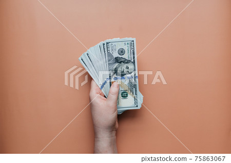 Bundle of dollars in hand on beige background 75863067