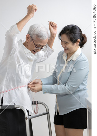 Old people measuring waist with tape measure,smiling asian senior woman raise hands feels happy satisfaction,proud of her weight loss as advised by doctor,success of diet,weight control,health care 75864360