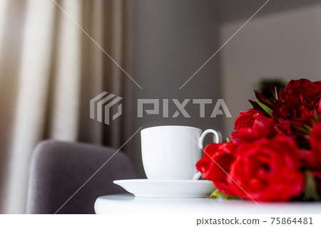 Bouquet of red tulips on table and white coffee cup. Concept for greeting card 75864481