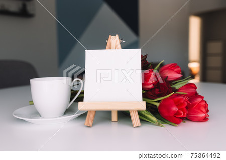 Bouquet of red tulips, coffee cup, empty white frame. Concept for greeting card Bouquet of red tulips, coffee cup, empty white frame. Concept for greeting card 75864492
