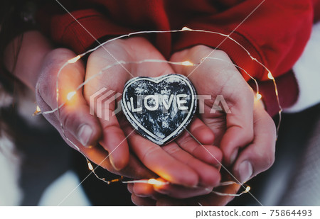 Hands holding stone heart with love text. Blurred background Hands holding stone heart with love text. Blurred background 75864493