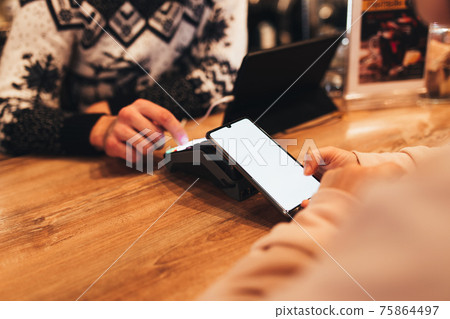 Cashless payment with NFC and phone in a cafe terminal. Blurred background 75864497