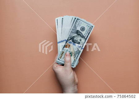 Bundle of dollars in hand on beige background 75864502