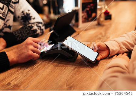 Cashless payment with NFC and phone in a cafe terminal. Blurred background 75864545