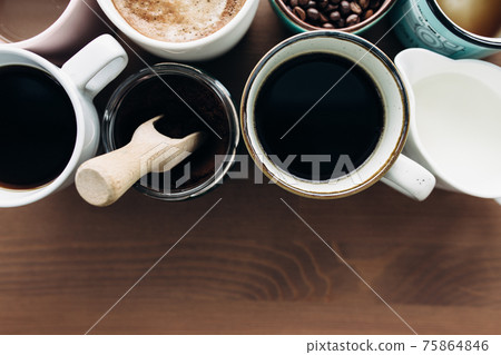 Multiple coffee cups, milk, beans and ground coffee in jar on wooden background 75864846