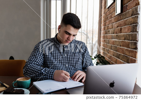 Man working at the laptop with a cup of coffee at home. Blurred background 75864972