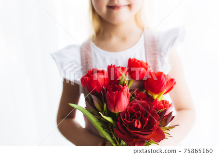 Smiling small girl holding bouquet of red tulips. Concept for greeting card Smiling small girl holding bouquet of red tulips. Concept for greeting card 75865160