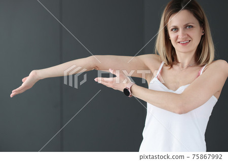 Young smiling woman showing her bent arm Young smiling woman showing her bent arm 75867992