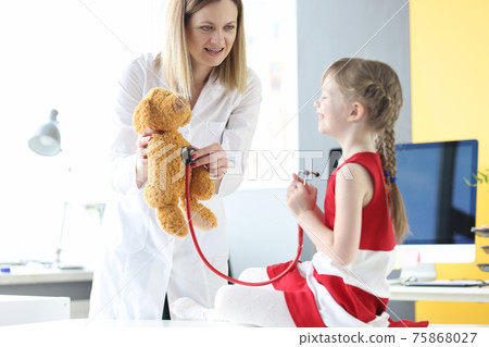 Little girl listening to toy bear with stethoscope together with doctor Little girl listening to toy bear with stethoscope together with doctor 75868027