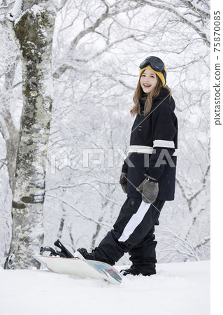 A young woman snowboarding at a snowy ski resort 75870085