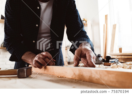 Carpenter makes pencil marks on a wood plank 75870194