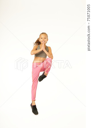 Cheerful female kid in sportswear jumping in studio 75871005