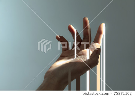Beautiful female hand catching streaks of light isolated on grey background. 75871102