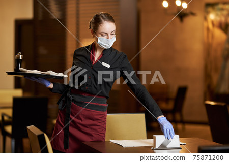 Mindful cafe worker using mask while serving the table Mindful cafe worker using mask while serving the table 75871200