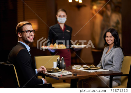 Lovely couple at restaurant table being served by responsible waitress Lovely couple at restaurant table being served by responsible waitress 75871213