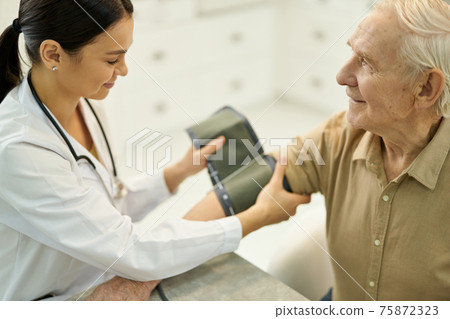 Professional medic preparing to measure blood pressure of senior gentleman 75872323