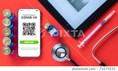 Immune passport. Coronavirus immunity certificate or vaccine passport on smartphone screen with doctor stethoscope, healthcare charts, syringe and medical equipment on hospital red background. Immune passport. Coronavirus immunity certificate or vaccine passport on smartphone screen with doctor stethoscope, healthcare charts, syringe and medical equipment on hospital red background. 75873919