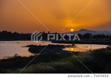 Sunset at the Larnaca salt lake witht he setting sun and wind turbines in the distance Sunset at the Larnaca salt lake witht he setting sun and wind turbines in the distance 75874854