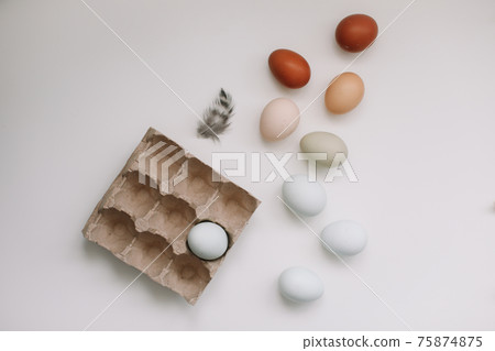 fresh chicken eggs of natural shades and colors in a recycled box on a white background fresh chicken eggs of natural shades and colors in a recycled box on a white background 75874875