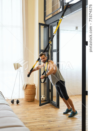 Athletic young man doing exercise with resistance band 75874876