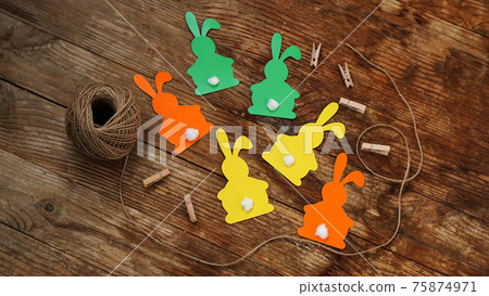 Easter bunnies made of paper on a wooden background. Create a decor for easter Easter bunnies made of paper on a wooden background. Create a decor for easter 75874971