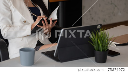 Woman with video conference note some data on notepad for protection covid-19.woman using tablet webinar video course at home office.- education or business online concept 75874972