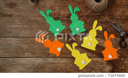 Easter bunnies made of paper on a wooden background. Create a decor for easter 75874980