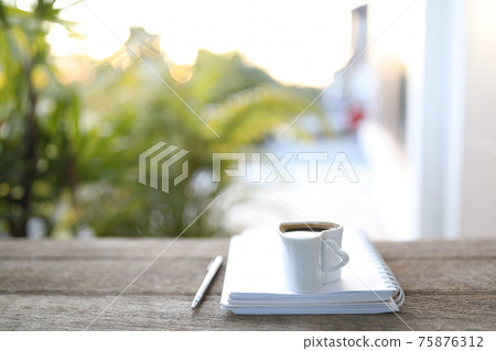 White coffee cup and open notebook on wooden table White coffee cup and open notebook on wooden table 75876312