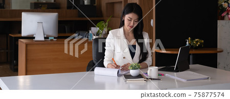 Business woman reading minute of meeting on her notebook in office. Business woman reading minute of meeting on her notebook in office. 75877574