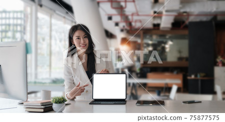 Business woman holding and pointing at digital tablet with blank screen in coffee shop. Business woman holding and pointing at digital tablet with blank screen in coffee shop. 75877575