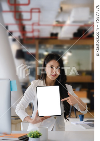Business woman holding and pointing at digital tablet with blank screen in coffee shop. Business woman holding and pointing at digital tablet with blank screen in coffee shop. 75877576