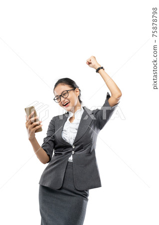 Beautiful businesswoman is holding and looking at the telephone while raising his hand with a happy expression Beautiful businesswoman is holding and looking at the telephone while raising his hand with a happy expression 75878798