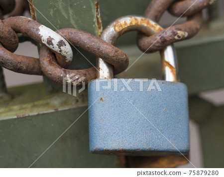 Close up of blue padlock with rusty chain locked at old green gate door, selective focus Close up of blue padlock with rusty chain locked at old green gate door, selective focus 75879280